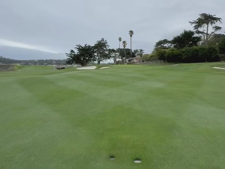 man cleaning his golf iron head with the original Grooveit brush, on a green fairway under a cloudy sky